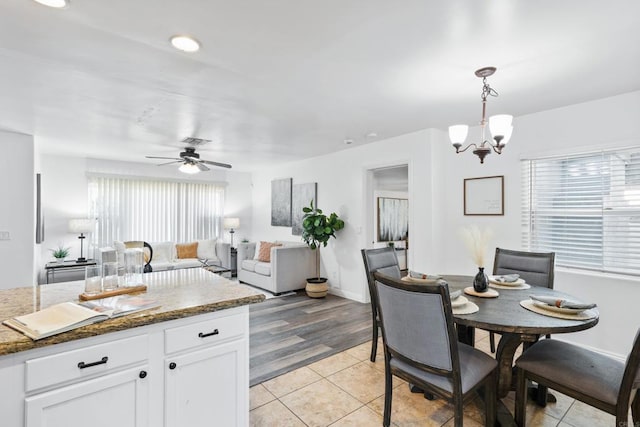 kitchen featuring white cabinetry, dark stone countertops, decorative light fixtures, ceiling fan with notable chandelier, and light tile patterned flooring