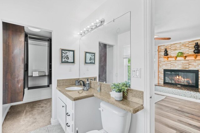 bathroom featuring toilet, vanity, a tiled fireplace, and tile patterned flooring