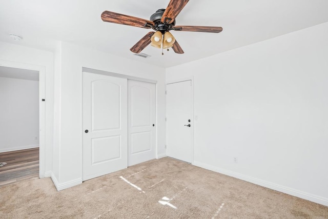 unfurnished bedroom featuring light carpet, a closet, and ceiling fan