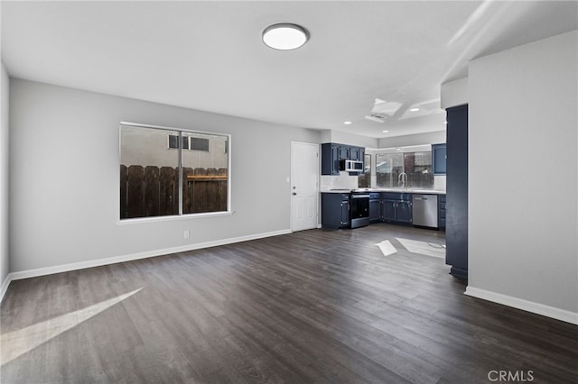 unfurnished living room featuring dark hardwood / wood-style flooring, sink, and a wealth of natural light