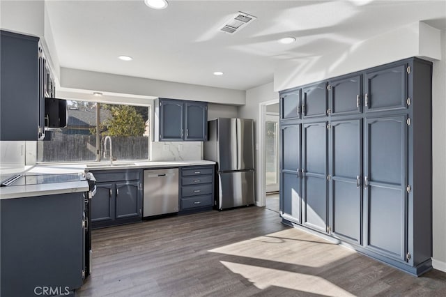 kitchen featuring sink, appliances with stainless steel finishes, backsplash, dark hardwood / wood-style floors, and blue cabinets