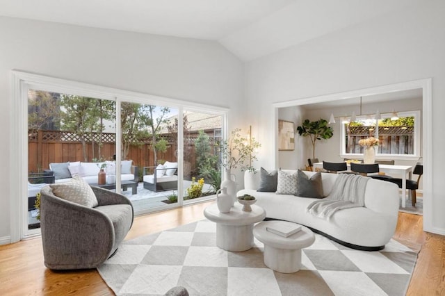 living room with a chandelier, vaulted ceiling, and light wood-type flooring