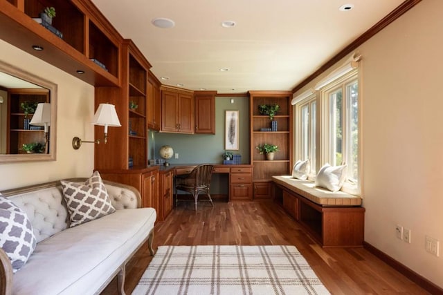 office featuring ornamental molding, built in desk, and dark hardwood / wood-style flooring