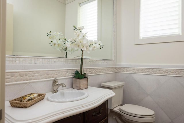 bathroom featuring vanity, tile walls, and toilet