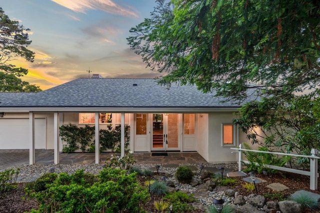 back house at dusk featuring a garage