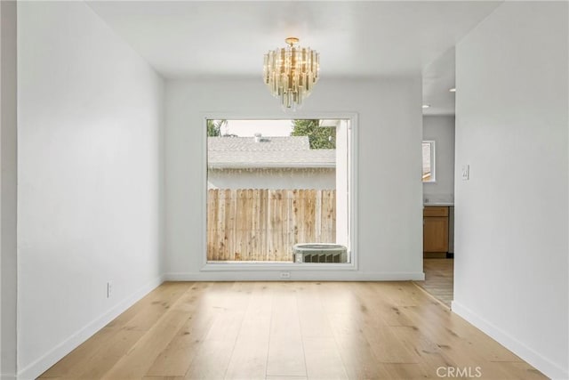 empty room with an inviting chandelier and light hardwood / wood-style floors