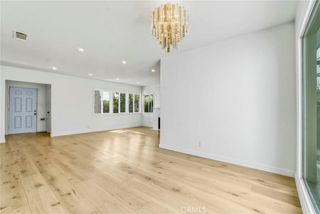 unfurnished living room featuring light hardwood / wood-style floors and an inviting chandelier