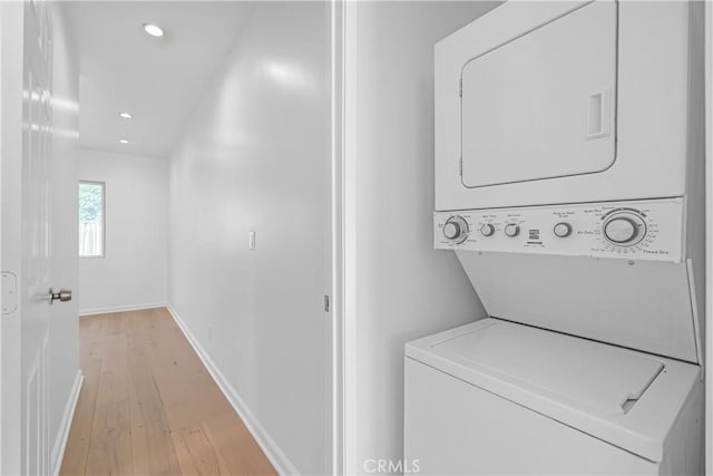 laundry area with stacked washer and clothes dryer and light wood-type flooring