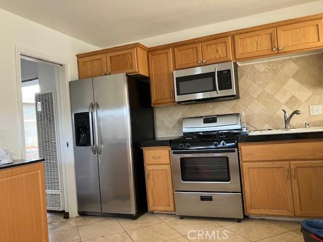 kitchen featuring stainless steel appliances, light tile patterned flooring, sink, and decorative backsplash