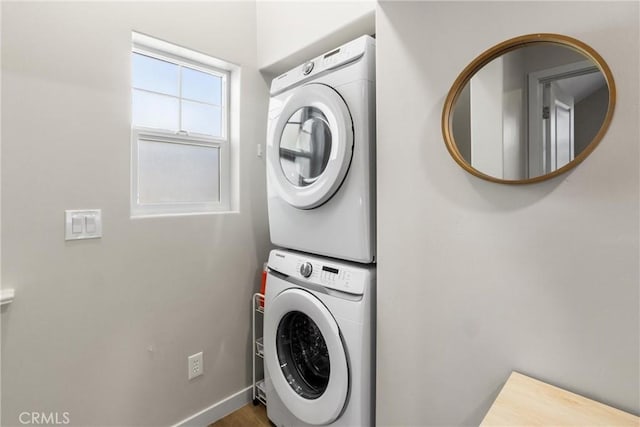 laundry area with stacked washer and clothes dryer, baseboards, and laundry area