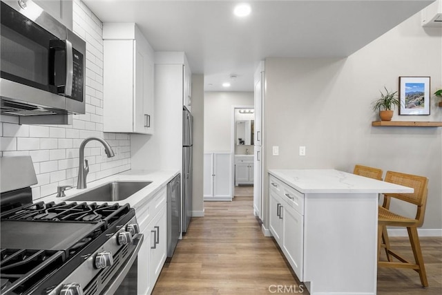 kitchen featuring a breakfast bar, light wood-style floors, stainless steel appliances, and a sink