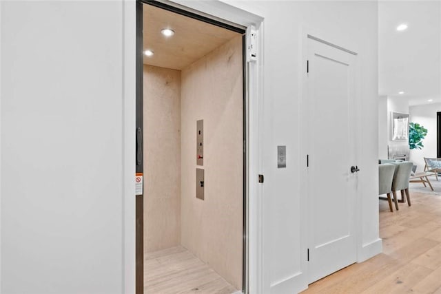 hall with elevator and light hardwood / wood-style floors