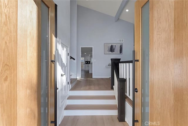 stairs with hardwood / wood-style flooring and high vaulted ceiling