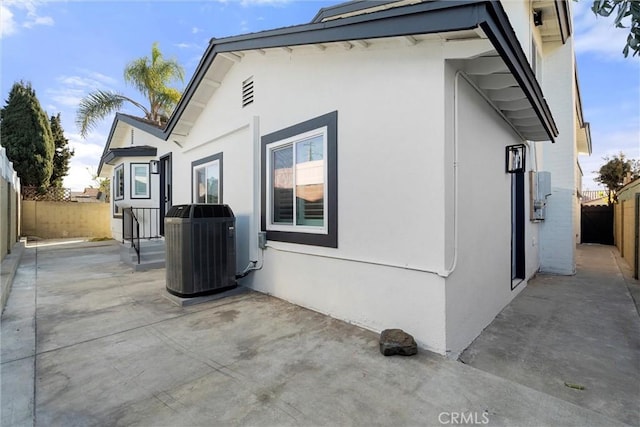 view of side of home with central AC unit and a patio