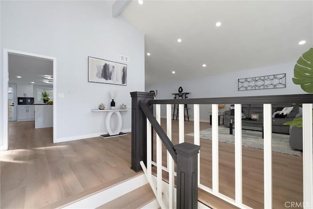 stairs featuring wood-type flooring and vaulted ceiling with beams