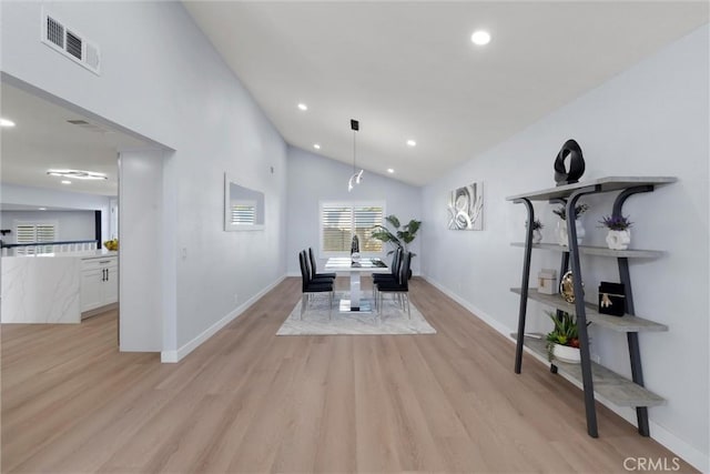 dining room with light hardwood / wood-style flooring and vaulted ceiling