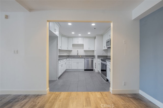 kitchen with white cabinets, stainless steel appliances, light wood-type flooring, and sink