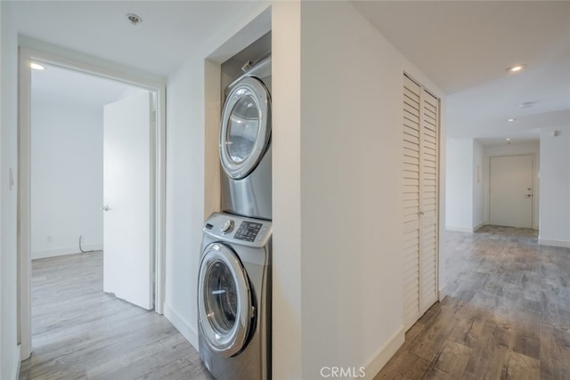 laundry room featuring stacked washer / dryer and light wood-type flooring