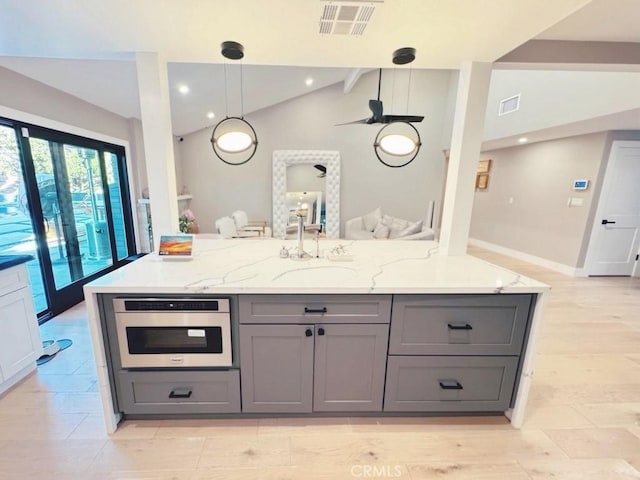 kitchen with sink, hanging light fixtures, gray cabinets, stainless steel oven, and light stone counters