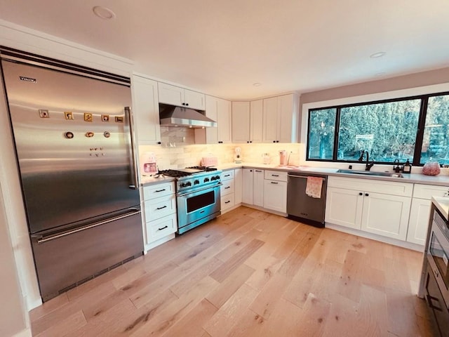 kitchen featuring decorative backsplash, sink, premium appliances, and white cabinets