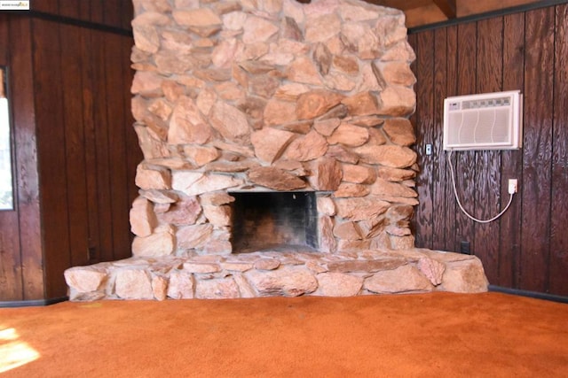 room details featuring wooden walls, a wall unit AC, a stone fireplace, and carpet floors