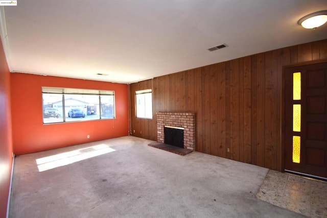 unfurnished living room featuring carpet, wooden walls, and a fireplace