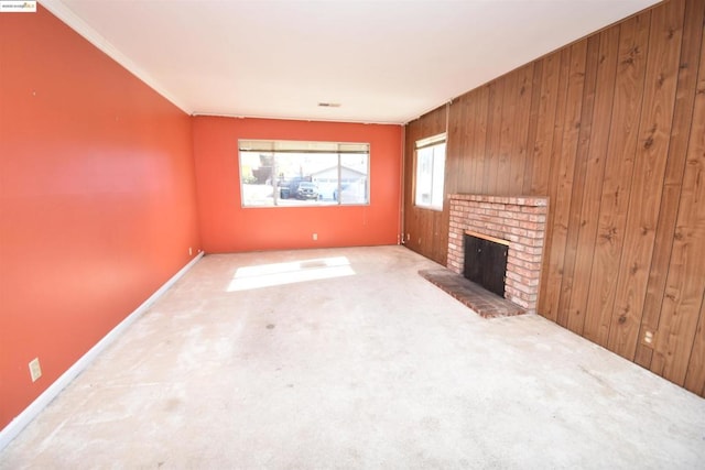 unfurnished living room with a fireplace, crown molding, wooden walls, and carpet floors