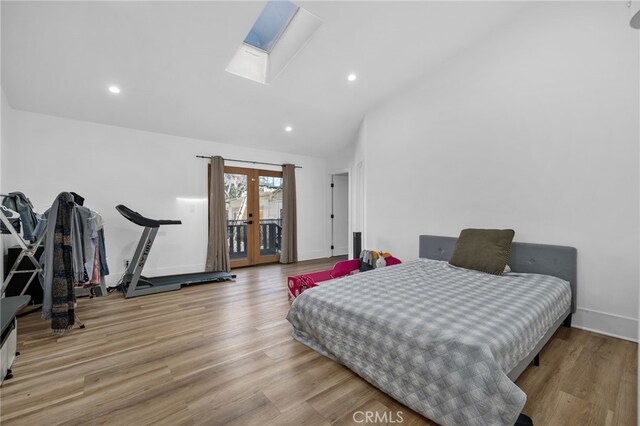 bedroom with light hardwood / wood-style floors, lofted ceiling with skylight, access to outside, and french doors