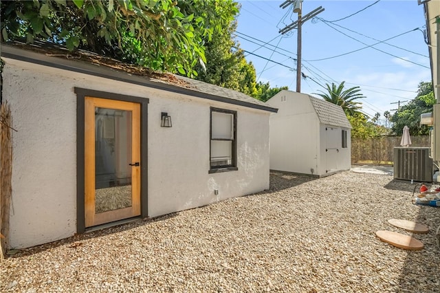 rear view of house featuring central air condition unit and a storage shed