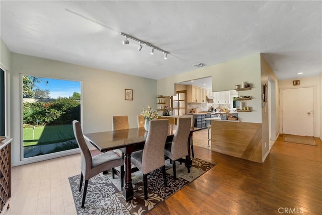 dining area featuring rail lighting and hardwood / wood-style flooring