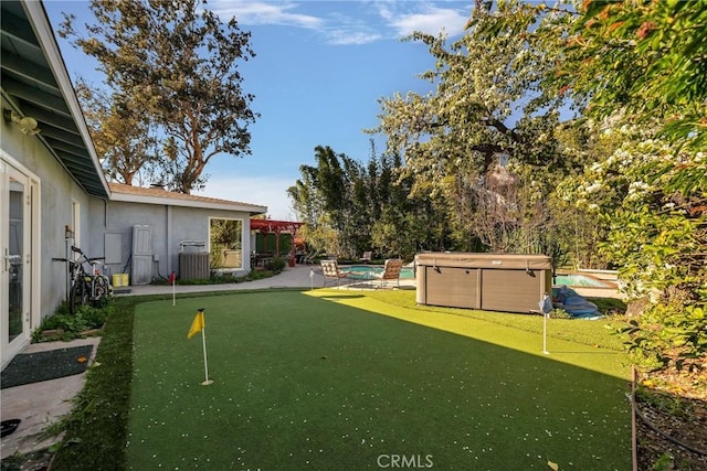 view of yard featuring central air condition unit and a swimming pool with hot tub