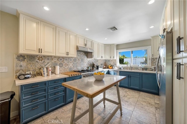 kitchen with sink, appliances with stainless steel finishes, tasteful backsplash, and blue cabinets