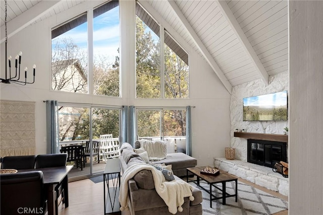 living room featuring wood-type flooring, a fireplace, a chandelier, high vaulted ceiling, and beam ceiling