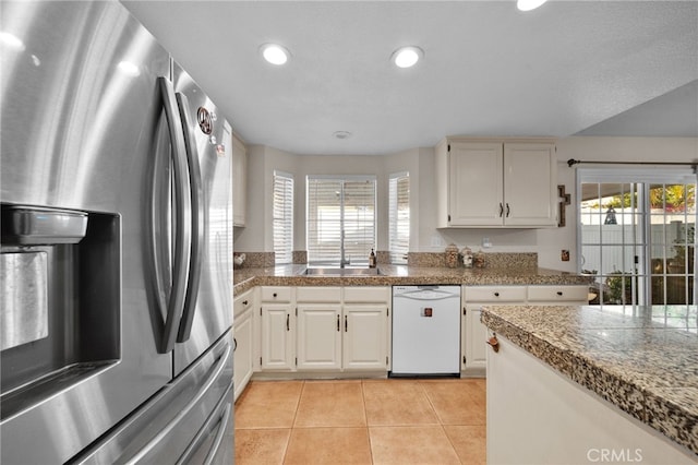 kitchen with dishwasher, white cabinetry, sink, stainless steel fridge, and light tile patterned floors