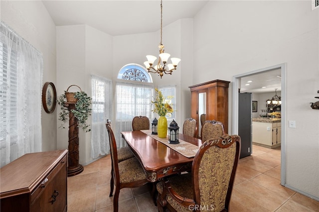 tiled dining space with a high ceiling and an inviting chandelier