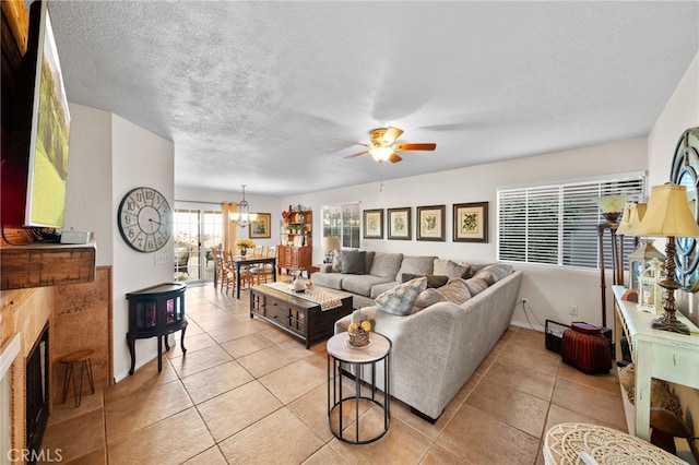 tiled living room featuring ceiling fan with notable chandelier and a textured ceiling