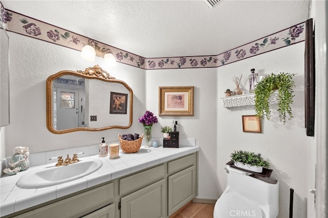 bathroom featuring a textured ceiling, toilet, vanity, and tile patterned flooring