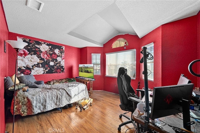 bedroom featuring hardwood / wood-style floors, a textured ceiling, and lofted ceiling