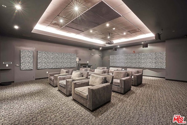 carpeted cinema room featuring a tray ceiling