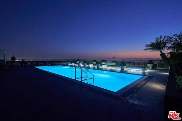 pool at dusk with a patio area