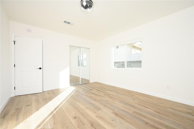 unfurnished bedroom featuring a closet and light wood-type flooring