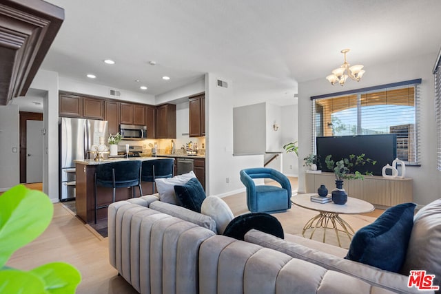 living room with an inviting chandelier and light hardwood / wood-style floors