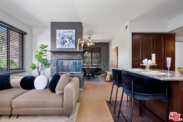 living room featuring a fireplace, light hardwood / wood-style flooring, and ceiling fan