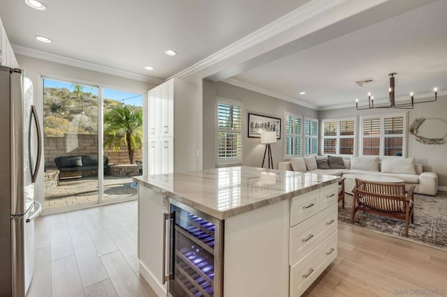 kitchen featuring white cabinetry, a center island, stainless steel refrigerator, beverage cooler, and light stone countertops