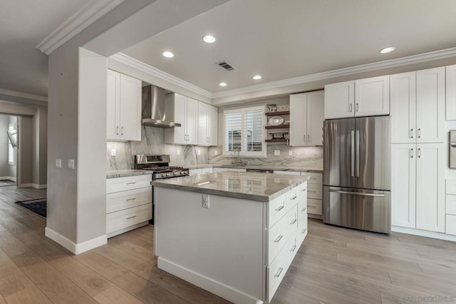 kitchen with a kitchen island, white cabinets, stainless steel appliances, light stone countertops, and wall chimney exhaust hood