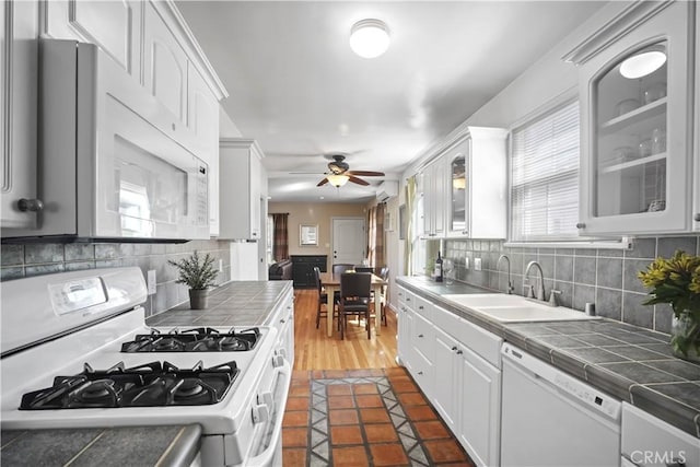 kitchen with sink, white appliances, white cabinetry, tasteful backsplash, and tile counters