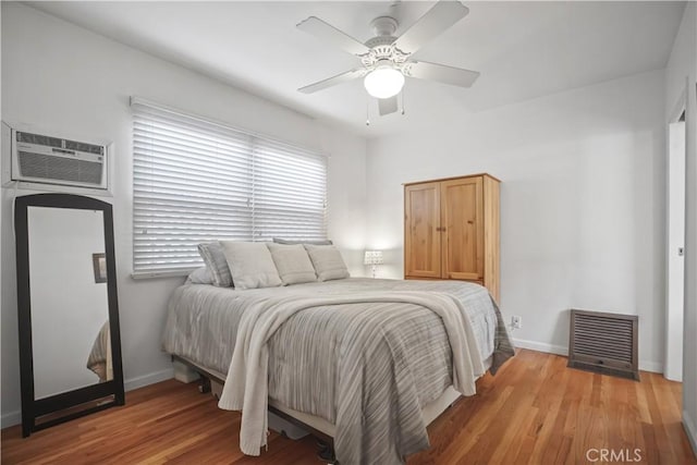 bedroom featuring hardwood / wood-style floors, a wall mounted AC, and ceiling fan