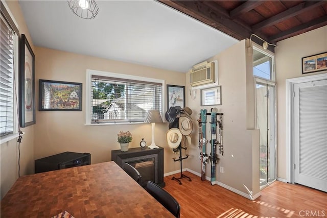 office featuring vaulted ceiling with beams, wooden ceiling, light hardwood / wood-style flooring, and an AC wall unit