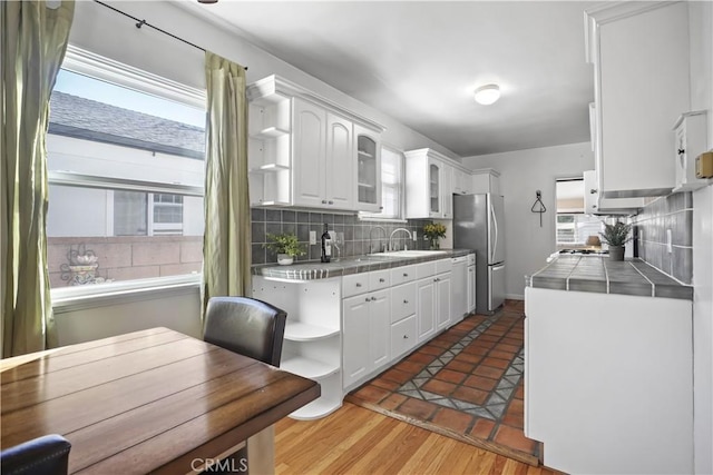 kitchen featuring white cabinetry, tile countertops, stainless steel fridge, and plenty of natural light