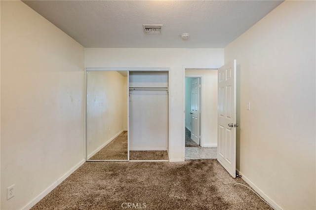 unfurnished bedroom featuring dark colored carpet, a textured ceiling, and a closet